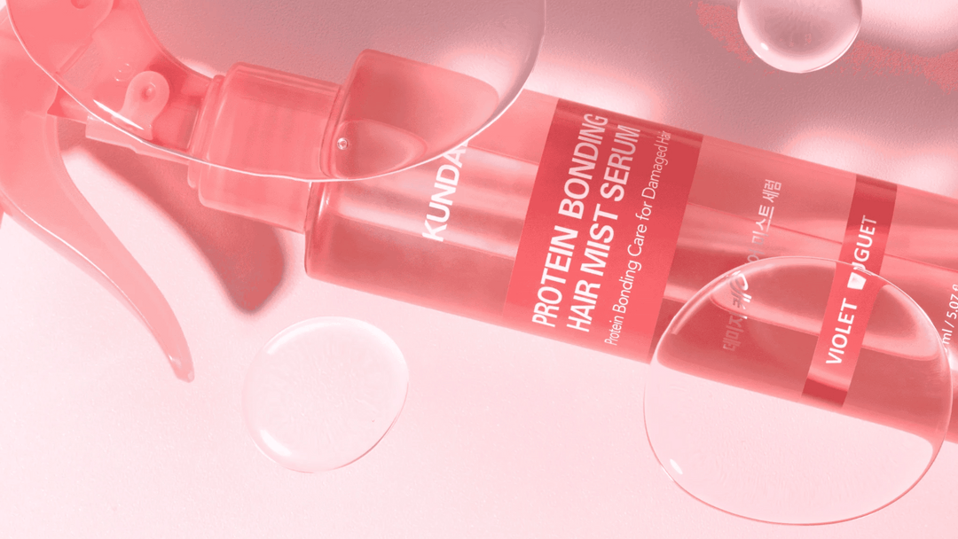 KUNDAL Protein Bonding Hair Mist Serum i rosa sprayflaska med texten Violet Bouquet, liggande mot rosa bakgrund med vattendroppar.