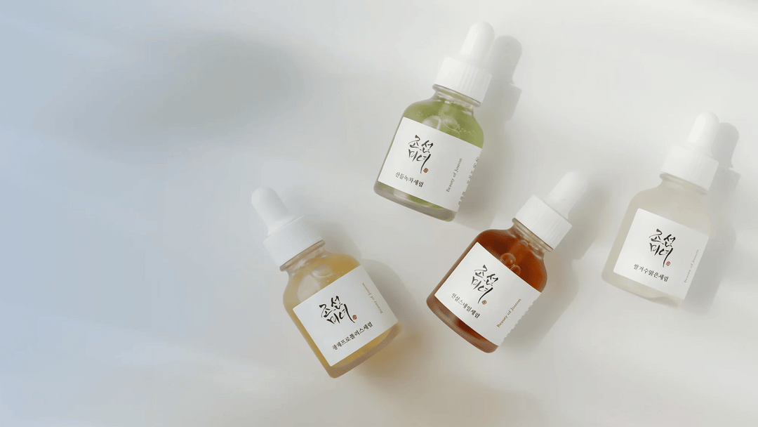 Fyra genomskinliga droppflaskor med ansiktserum från Beauty of Joseon i olika färger, mjukt upplysta mot en ljus bakgrund.
