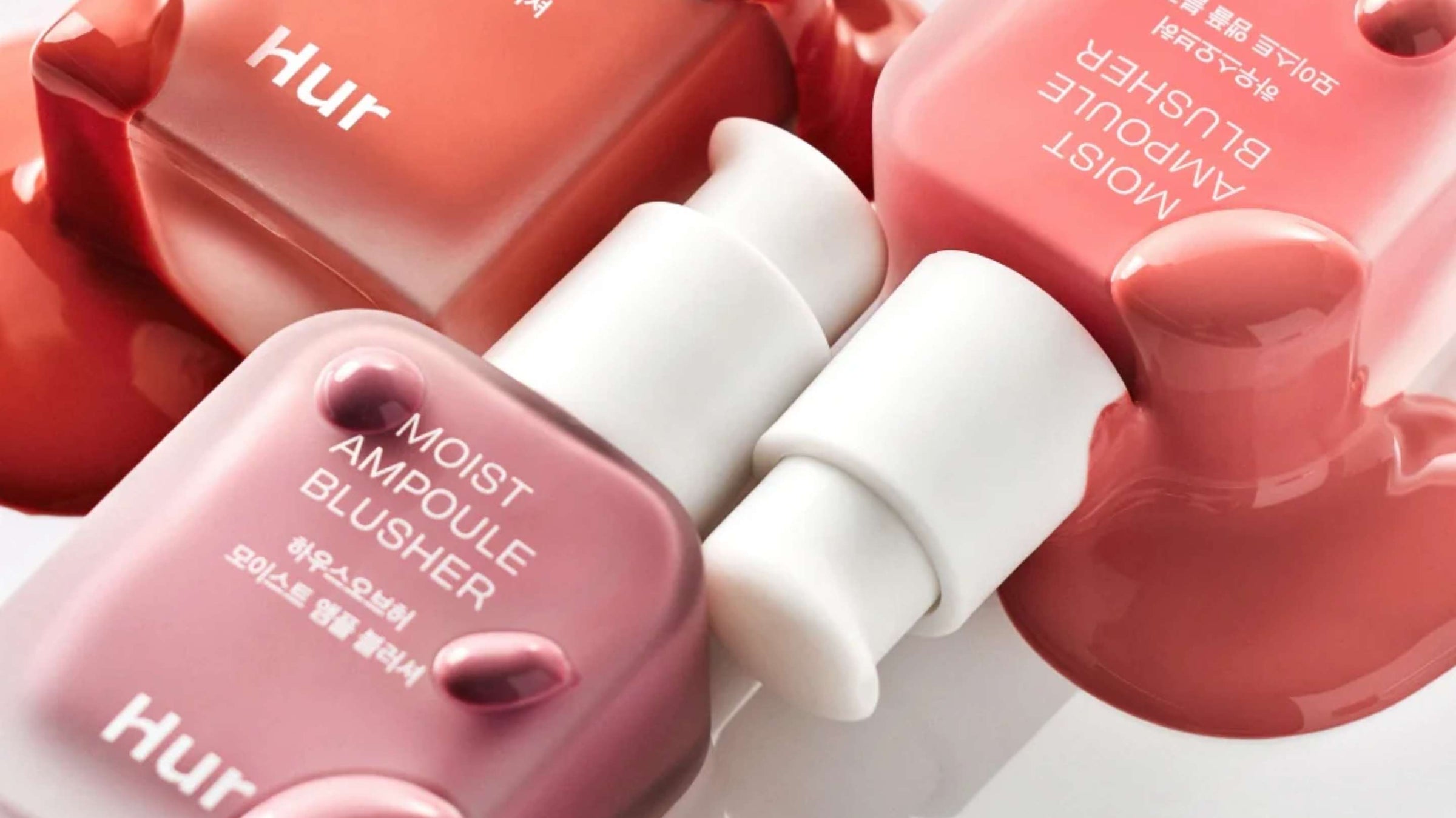 Bilden visar två hjärtformade behållare från märket lilybyred, en i en mörkare röd nyans och en i en ljusare rosa ton. Designen är lekfull och romantisk, vilket antyder att produkterna inuti kanske är makeupartiklar som rouge eller highlighters.