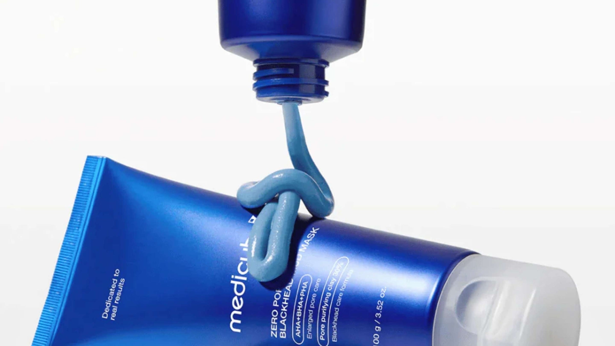 En vit flaska med COSRX BHA Blackhead Power Liquid, liggande på en vit yta med reflektion.