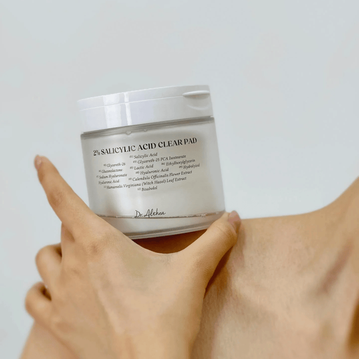 Dr. Althea 2% Salicylic Acid Clear Pad tenu à la main. Tampons tonifiants avec 2% d'acide salicylique qui exfolient doucement, apaisent la peau et améliorent la texture de la peau.