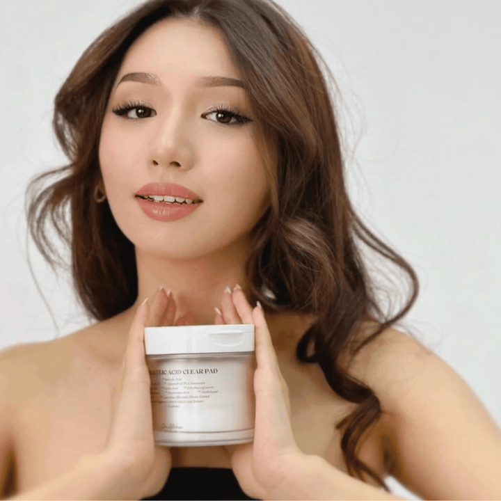 Le modèle tient Dr. Althea 2% Salicylic Acid Clear Pad devant le visage. Tampons tonifiants exfoliants avec acide salicylique qui nettoient les pores, équilibrent le sébum et offrent une peau plus claire.