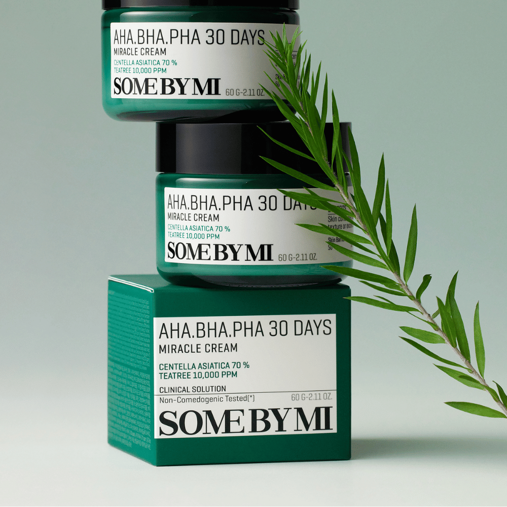 Une image montrant deux pots de "SOME BY MI AHA, BHA, PHA 30 Days Miracle Cream" empilés sur une boîte teintée de vert. La crème, riche en centella asiatica et en huile de tea tree, est conçue pour améliorer la qualité de la peau et soulager les peaux à problèmes. Elle agit en hydratant et en apaisant.