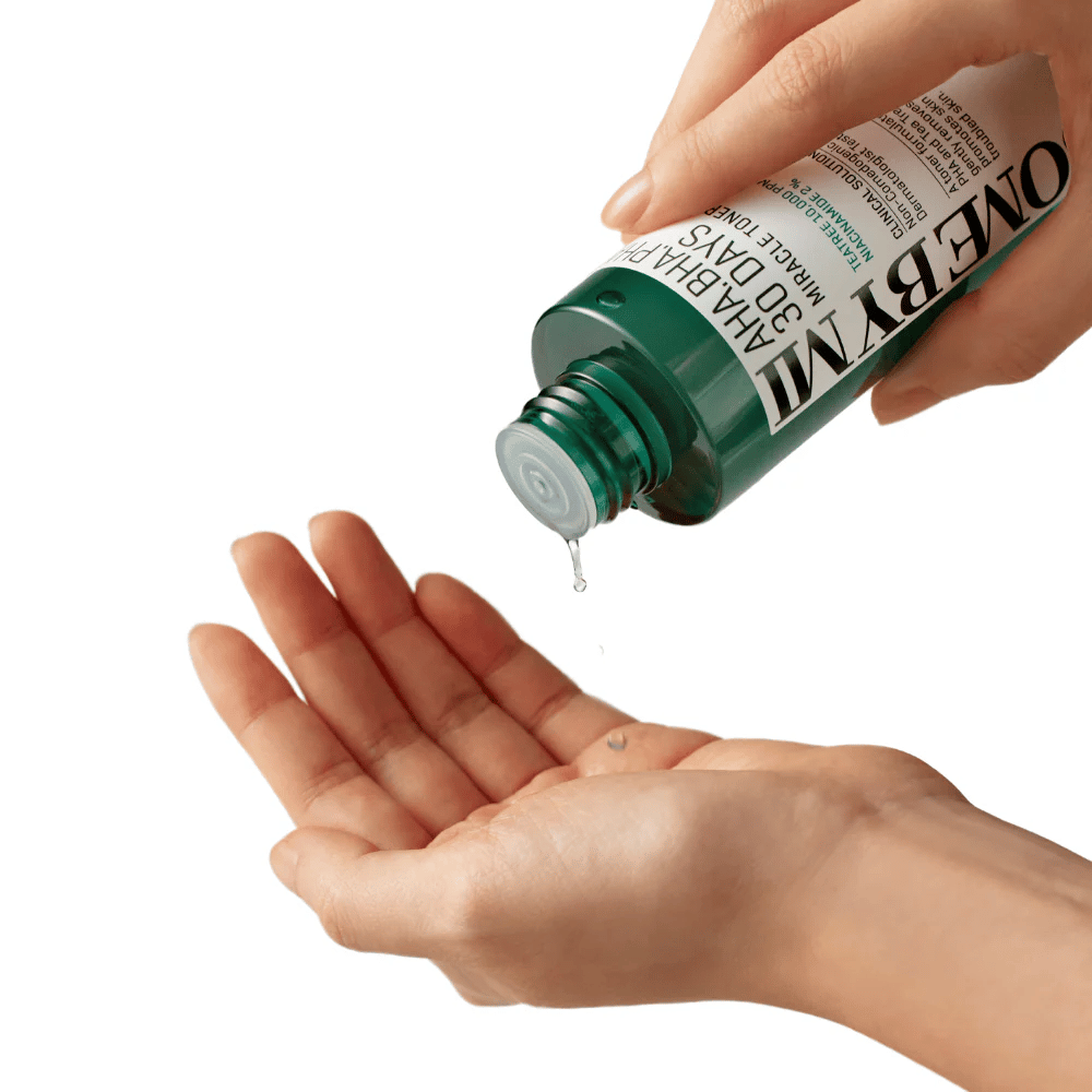 Une main tient une bouteille verte avec le texte "AHA, BHA, PHA 30 Days Miracle Toner" et presse un liquide clair dans la paume de l'autre main, prêt à être utilisé.