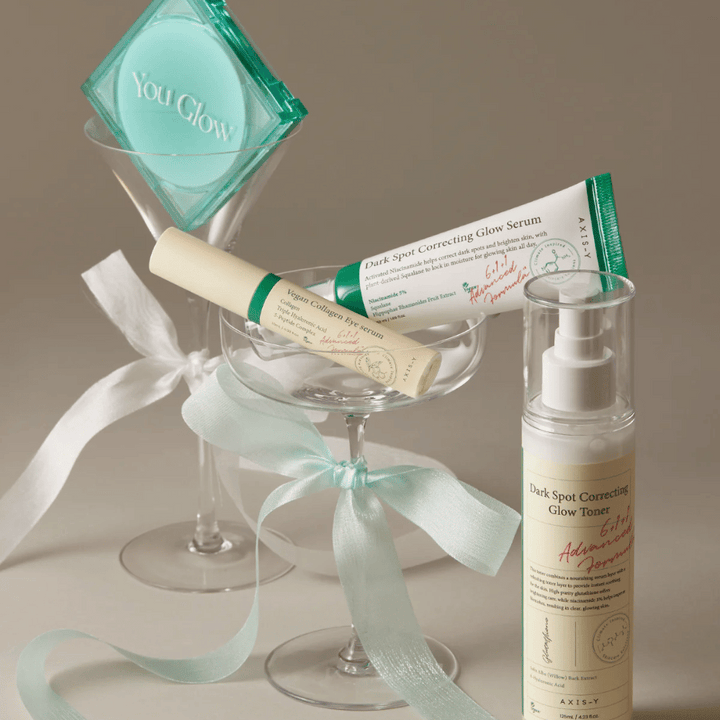 Image de Kit de soin de la peau de AXIS-Y avec sérum pour les yeux, sérum et toner – élégamment disposés dans un verre à cocktail avec un ruban de soie, parfait pour une présentation de cadeau luxueuse.