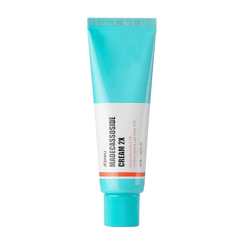 Un tube avec A'PIEU Madecassoside Cream 2X, avec une couleur turquoise clair en haut qui passe au blanc vers le bas. Le tube a un texte clair indiquant la marque et le nom du produit ainsi que l'ingrédient actif Madecassoside 2%. Une couleur accent orange fait une bande autour du tube. Le produit semble être une crème pour la peau axée sur les soins et la réparation de la peau. L'arrière-plan est neutre pour garder le focus sur le produit.