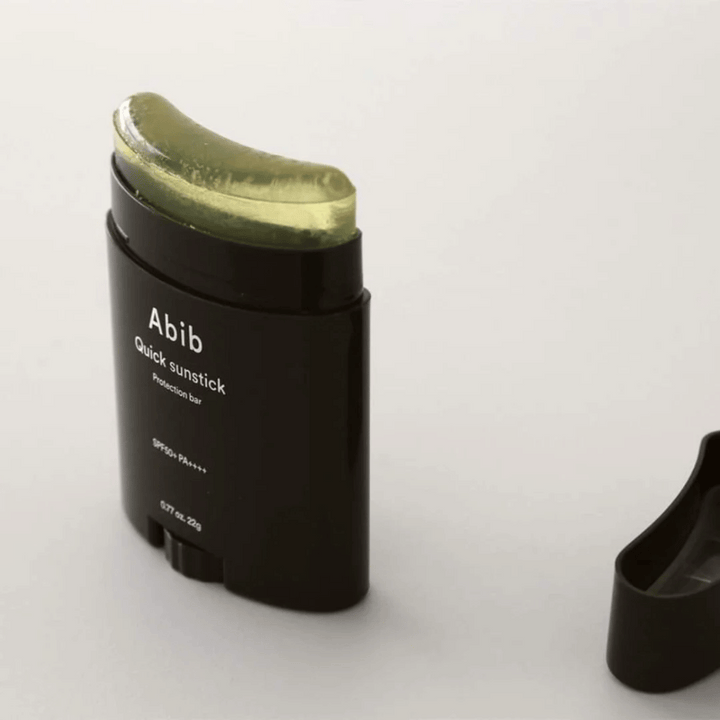 Un tube noir avec un bouchon vert, contenant Quick Sunstick Protection Bar SPF50+ PA++++ 22g de Abib pour la protection solaire.