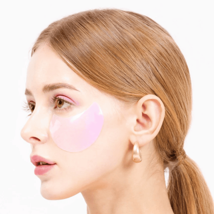 Un modèle porte un patch pour les yeux en hydrogel rose sous l'œil, hydratant et rajeunissant la peau.