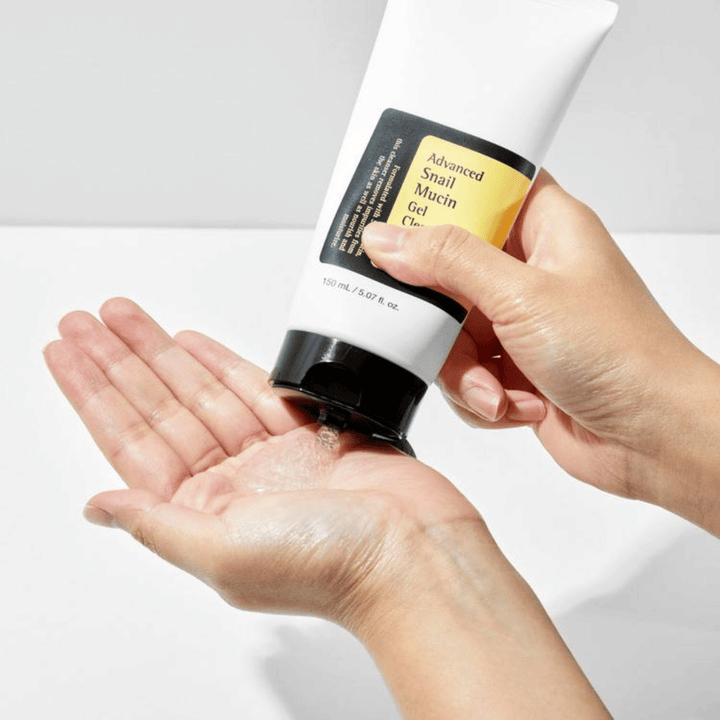 Main appliquant COSRX Advanced Snail Mucin Gel Cleanser – nettoyant gel doux avec mucine d'escargot qui nettoie en profondeur et préserve l'équilibre hydrique de la peau.