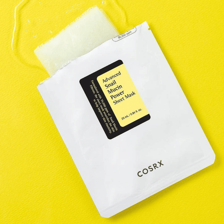 COSRX Advanced Snail Mucin Power Sheet Mask sur fond jaune, un masque facial hydratant et réparateur avec sécrétion d'escargot pour une élasticité et une luminosité accrues.