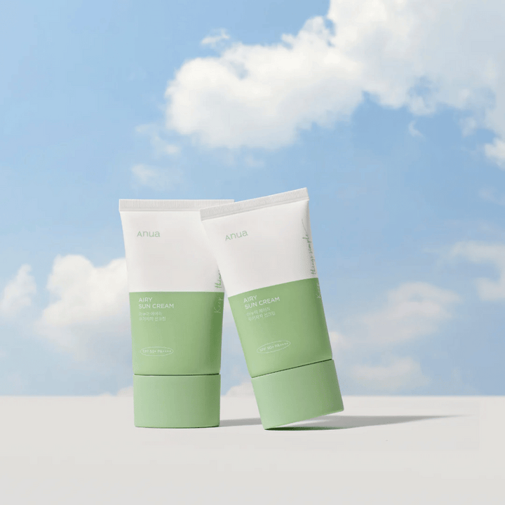 Deux tubes de Anua Airy Sun Cream contre un ciel avec des nuages blancs.