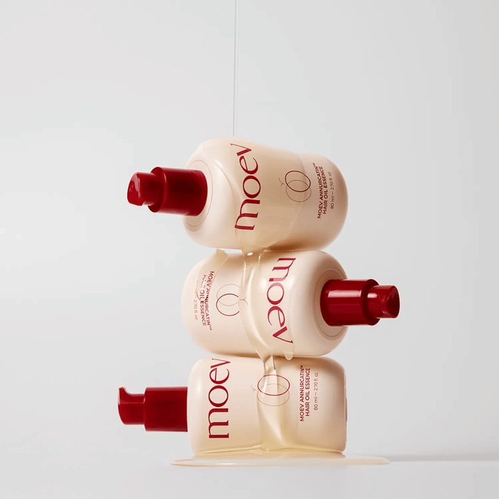 Trois bouteilles MOEV Annurcatin Hair Oil Essence empilées – huile capillaire nourrissante avec pomme Annurca et biotine qui renforce, protège et donne aux cheveux brillance et élasticité.