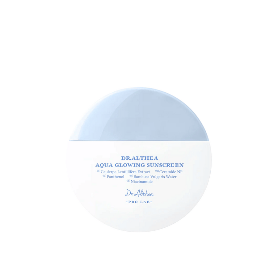 Image produit de Dr. Althea Aqua Glowing Sunscreen – une crème solaire ronde dans un emballage blanc et bleu clair avec du texte en bleu qui met en avant des ingrédients hydratants comme la niacinamide et les céramides.