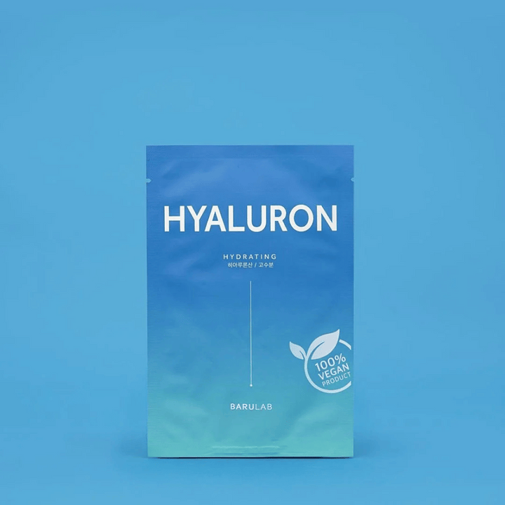 Un emballage de BARULAB masque "HYALURON Hydrating", marqué comme "100% Produit Végétalien", devant un fond bleu uniforme. L'emballage a un dégradé de couleur du bleu foncé au bleu clair.