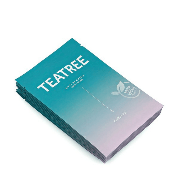 Une pile d'emballages de BARULAB masques "TEATREE Anti Blemish", tous marqués comme "Produit 100% Végan". Les emballages ont une couleur turquoise uniforme.