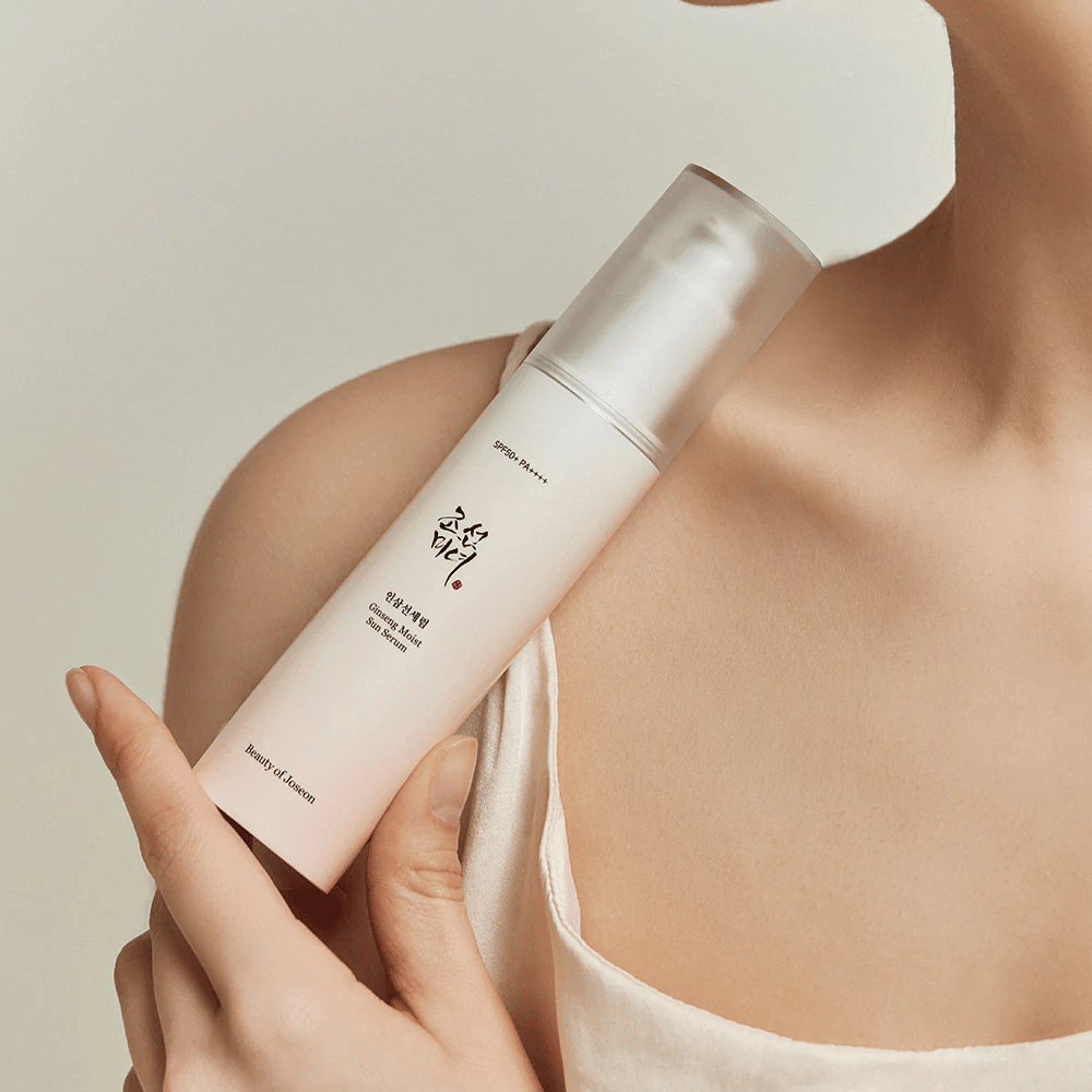 Une femme tenant une bouteille de Beauty of Joseon's Ginseng Moist Sun Serum SPF 50+ PA++++, offrant une protection SPF 50+ PA++++ et des bienfaits pour la peau.