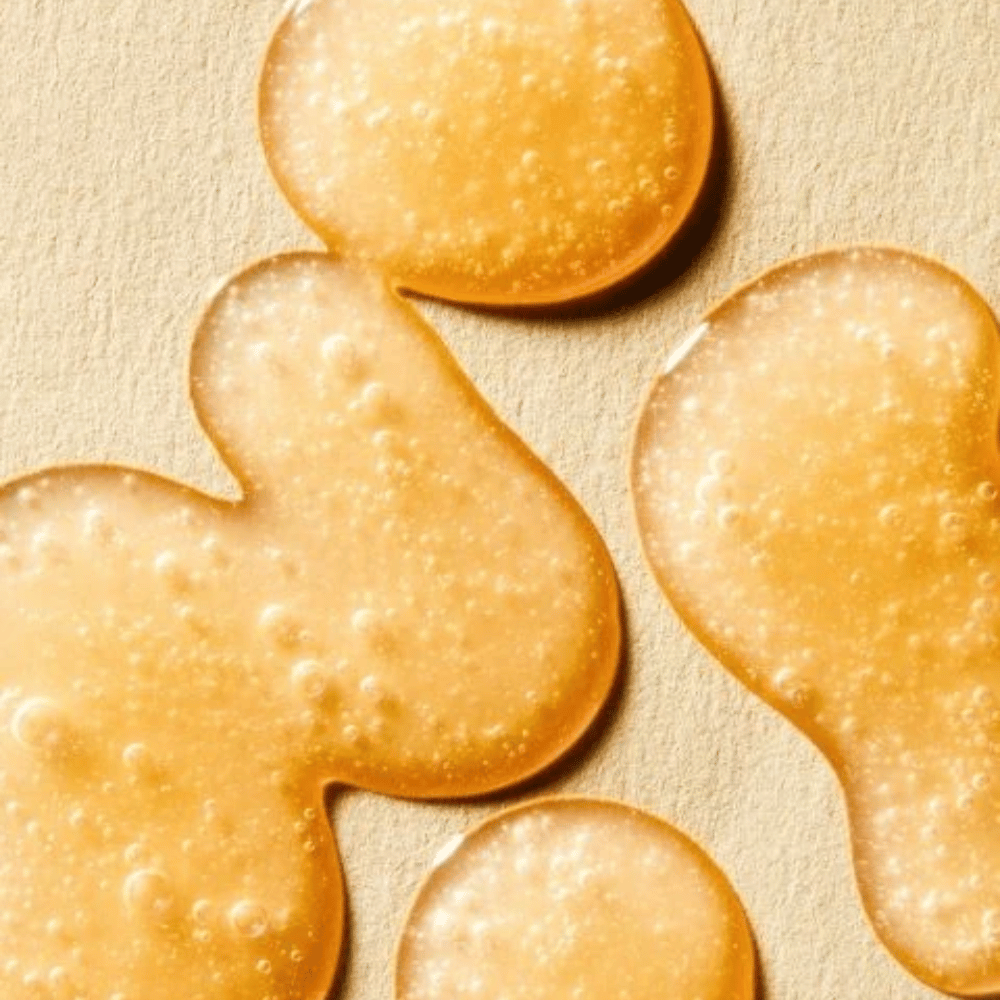 Image de texture montrant la formule dorée du sérum avec de petites bulles et une consistance légèrement gélifiée.