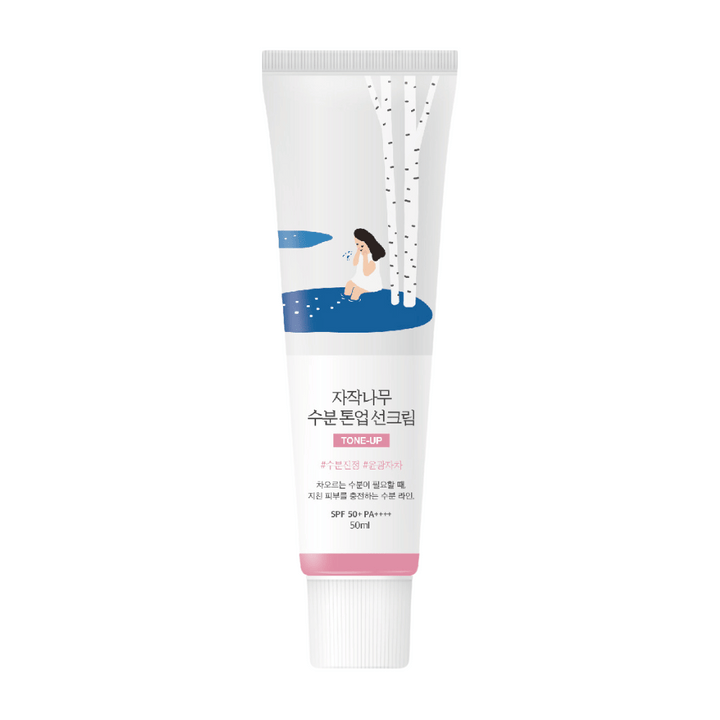 Un tube blanc avec Birch Juice Moisturizing Tone Up Sunscreen. Le tube a une illustration d'une femme assise près d'un bouleau à côté d'une flaque d'eau. Le texte sur le tube est en coréen et indique que le produit a SPF 50+ PA++++ et contient 50 ml.