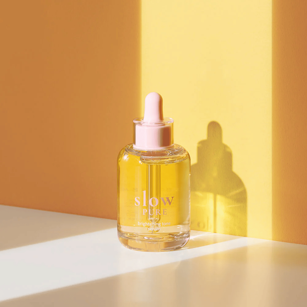 Slow Pure Brightening Tone Serum dans une lumière jaune ensoleillée, symbolise l'éclat et l'énergie pour la peau.