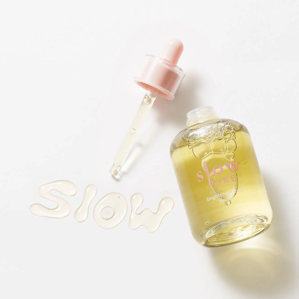 Slow Pure Brightening Tone Serum avec une pipette ouverte, texte écrit en sérum à la surface : "Slow".