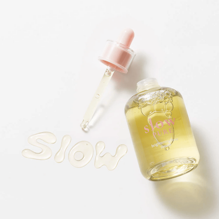 Slow Pure Brightening Tone Serum avec une pipette ouverte, texte écrit en sérum à la surface : "Slow".
