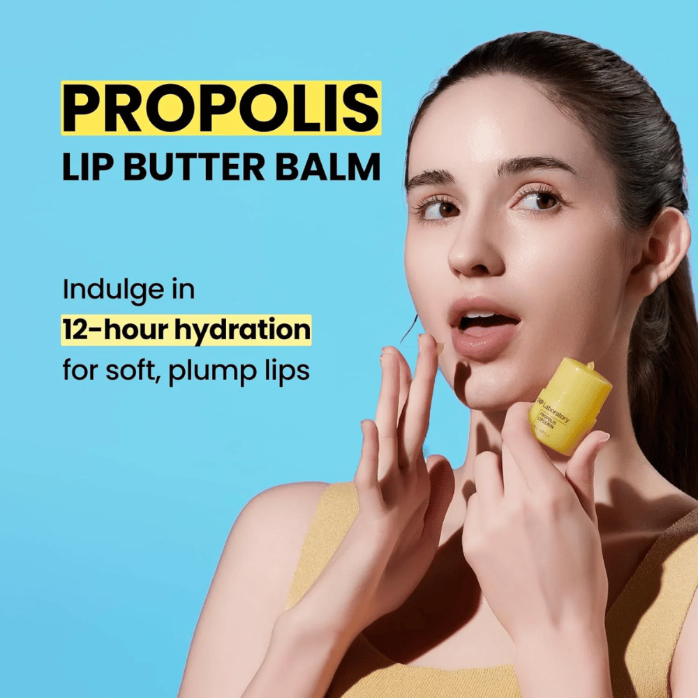 Une femme applique CNP Laboratory Propolis Lip Butter Balm, mise en valeur sur un fond bleu. Le produit promet 12 heures d'hydratation pour des lèvres douces et pulpeuses, illustré par un tube jaune qu'elle tient à la main.