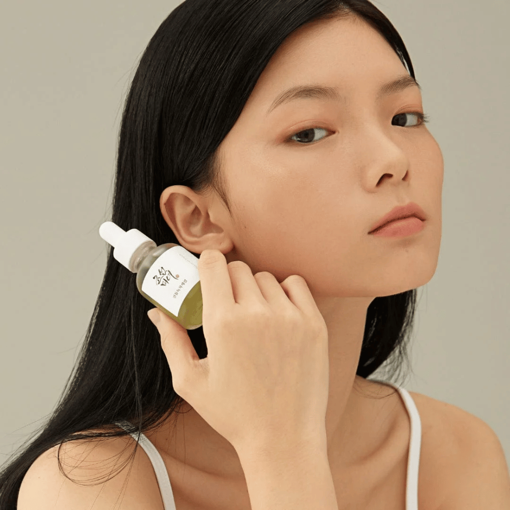 Modèle tenant Beauty of Joseon Calming Serum à la joue - thé vert et panthénol qui renforce la barrière cutanée.