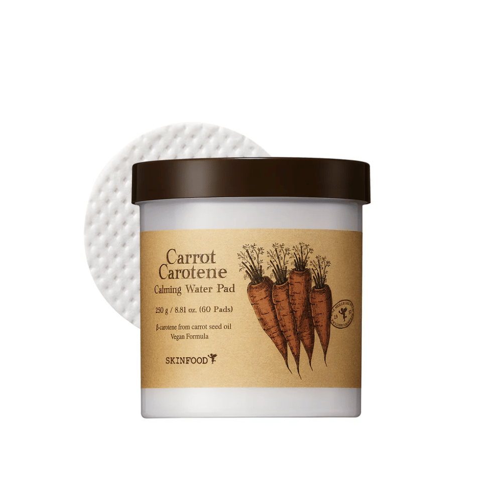 Un pot "Carrot Carotene Calming Water Pad" de SKINFOOD. Le pot contient 60 tampons et est marqué avec une image de carottes. Le produit, qui est à base d'huile de graines de carotte, est vegan et conçu pour apaiser la peau.