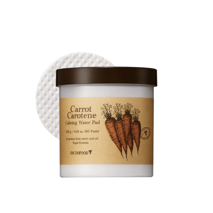 Un pot "Carrot Carotene Calming Water Pad" de SKINFOOD. Le pot contient 60 tampons et est marqué avec une image de carottes. Le produit, qui est à base d'huile de graines de carotte, est vegan et conçu pour apaiser la peau.