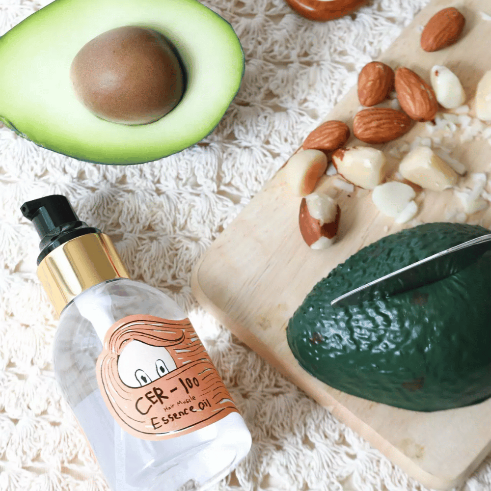 Elizavecca CER-100 Hair Muscle Essence Oil ingrédients – gros plan avec avocat et huiles végétales montrant une huile capillaire riche en nutriments qui aide à adoucir et à nourrir les cheveux.