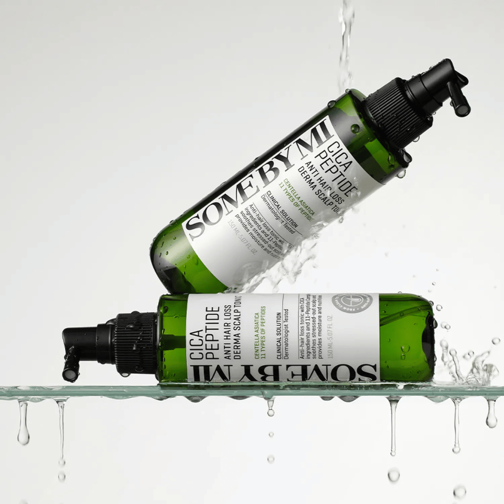 Deux bouteilles SOME BY MI Cica Peptide Anti Hair Loss Derma Scalp Tonic sont dans et au-dessus de l'eau avec des gouttes éclaboussant, bouteilles vertes avec un pulvérisateur noir et une étiquette blanche.