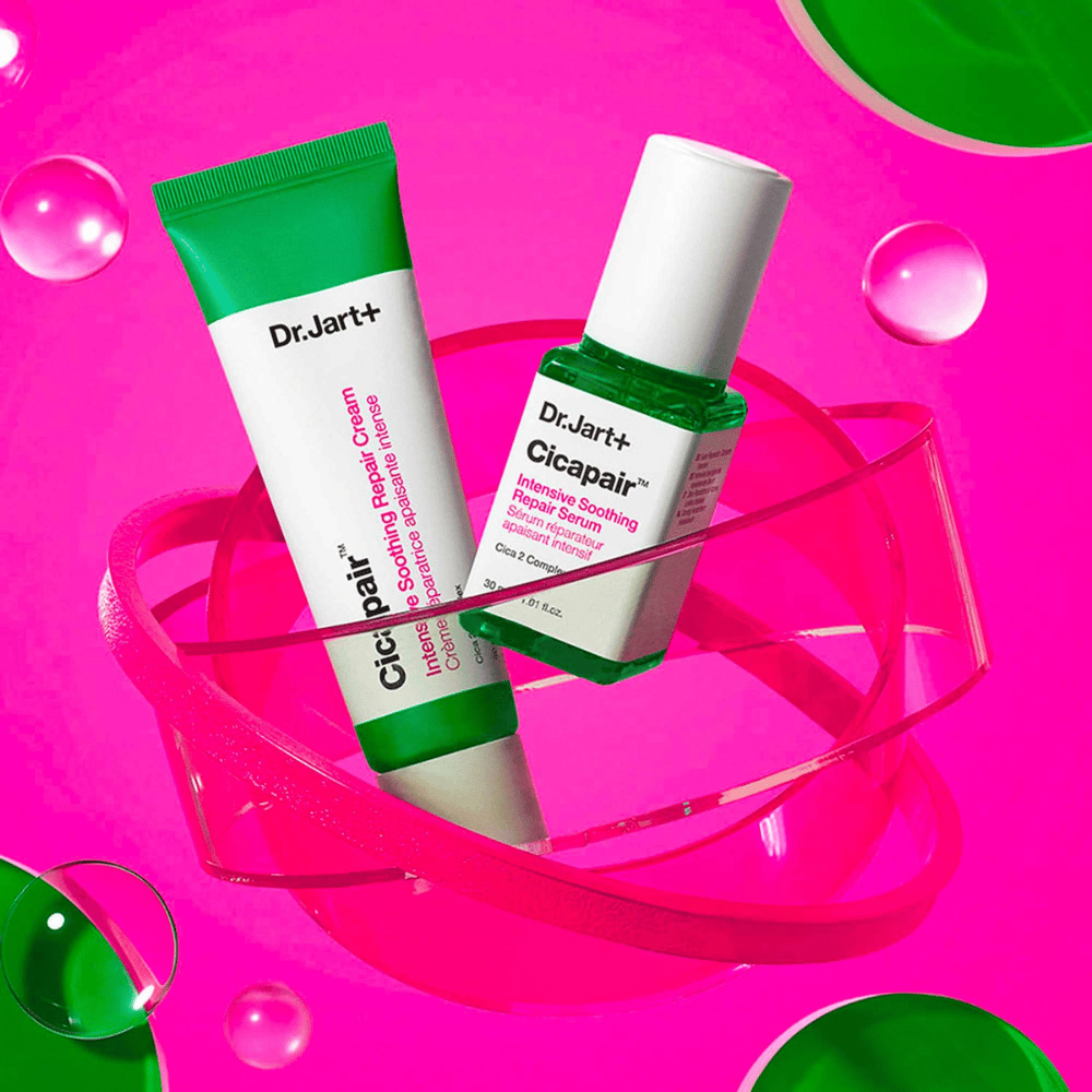 Dr.Jart+ Cicapair Intensive Soothing Repair Cream et Serum dans des emballages verts, qui reposent sur une base circulaire rose. Les produits sont conçus pour apaiser et réparer la peau irritée.