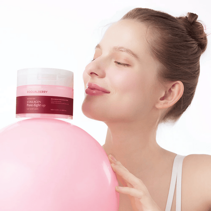 Une femme se tient avec une balle rose et un pot Collagen Pore-Tight Up Gel Toner Pads, tout en souriant et en tenant le pot près de son visage. Le pot est marqué avec le nom du produit et contient des tampons de toner qui aident à raffermir la peau et à réduire la taille des pores.