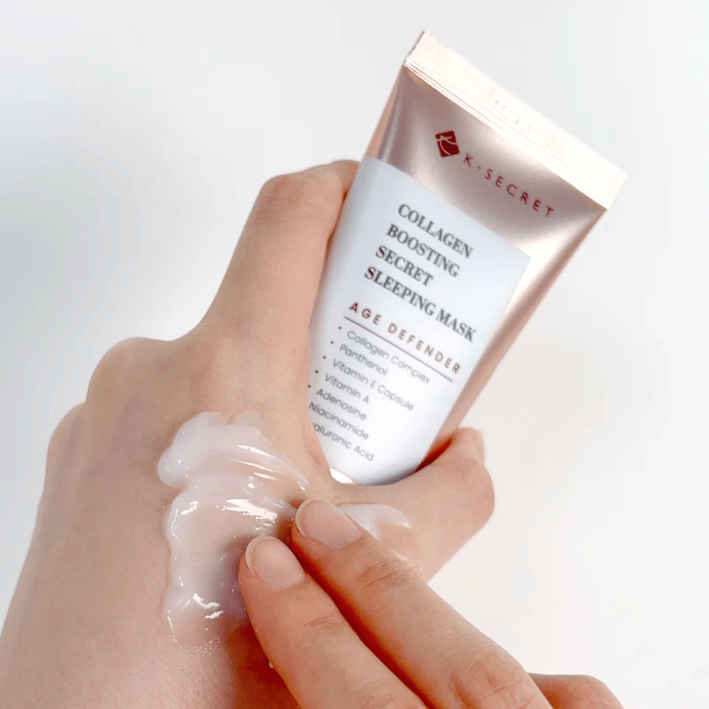 Une main tient Collagen Boosting Secret Sleeping Mask tandis que l'autre applique une quantité généreuse de crème sur le dessus de la main - montrant la consistance et l'application du produit.