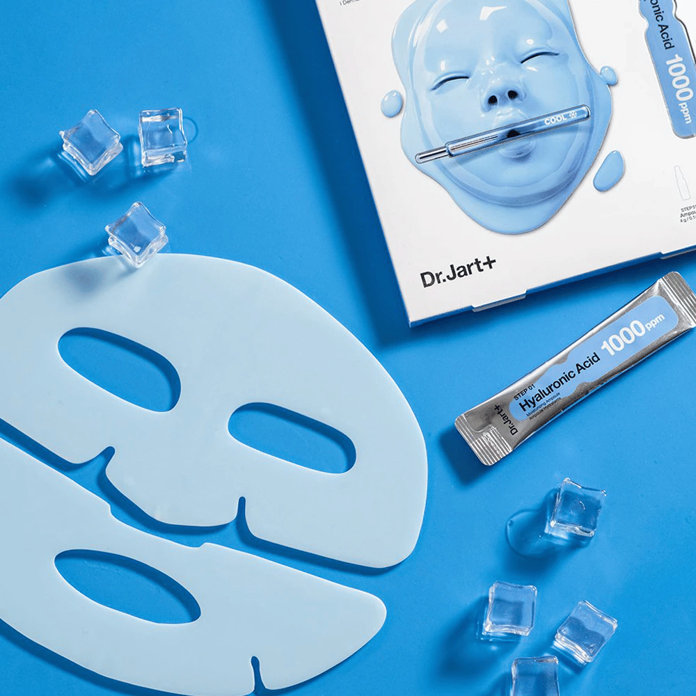 Dr.Jart+ Cryo Rubber Moisturizing Mask avec un masque en caoutchouc bleu en deux parties, des glaçons, une ampoule d'acide hyaluronique et un emballage sur fond bleu.