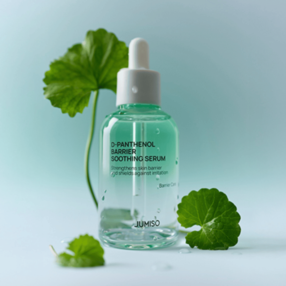 Jumiso D-Panthenol Barrier Soothing Serum dans une bouteille en verre transparent avec pipette, placée avec des feuilles vertes en arrière-plan.