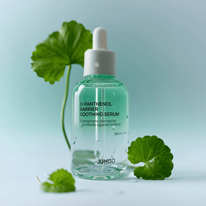 Jumiso D-Panthenol Barrier Soothing Serum dans une bouteille en verre transparent avec pipette, placée avec des feuilles vertes en arrière-plan.