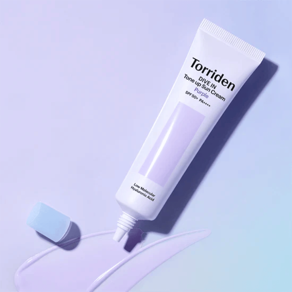 Tube ouvert de Torriden DIVE IN Tone Up Sun Cream Purple avec une texture de crème solaire teintée de violet qui montre la formule correctrice de couleur du produit.