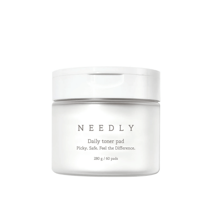 Un pot blanc avec Needly Daily Toner Pad. L'emballage a un texte minimaliste qui décrit le produit et contient 280 g, soit 60 tampons de toner. Le texte dit 'Picky. Safe. Feel the Difference.