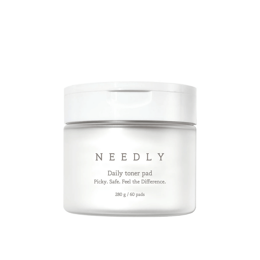 Un pot blanc avec Needly Daily Toner Pad. L'emballage a un texte minimaliste qui décrit le produit et contient 280 g, soit 60 tampons de toner. Le texte dit 'Picky. Safe. Feel the Difference.