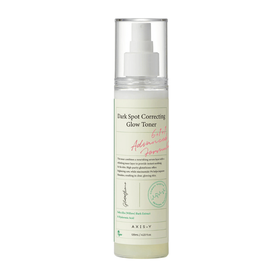 Une image d'une bouteille du produit "AXIS-Y Dark Spot Correcting Glow Toner". La bouteille est transparente avec une étiquette blanche et du texte en noir et vert. Le produit est un toner sous forme de spray, et la bouteille contient 125 ml (4,23 fl. oz). L'étiquette mentionne des ingrédients clés tels que l'extrait d'écorce de saule et l'acide hyaluronique.