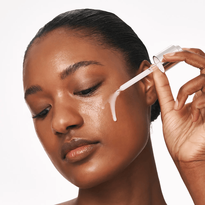 Une personne applique Deep Collagen Power Boosting Cream in Serum sur la joue avec une pipette. Le sérum donne une peau plus ferme, hydratée et éclatante.