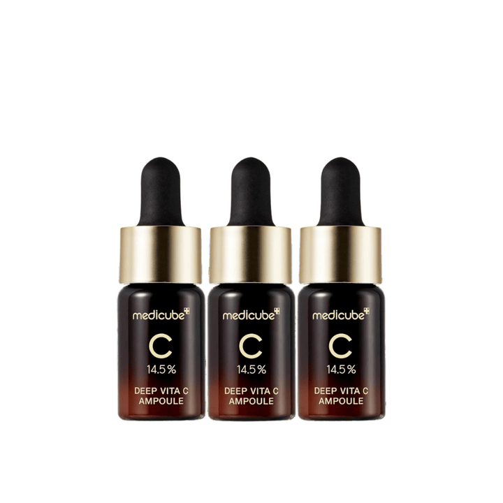 Trois flacons de Medicube Deep Vita C Ampoule, avec 14,5 % de vitamine C, disposés en ligne. Les flacons ont un design élégant avec une base brun foncé et un bouchon doré. Parfait pour un teint plus lumineux et une texture de peau plus uniforme.