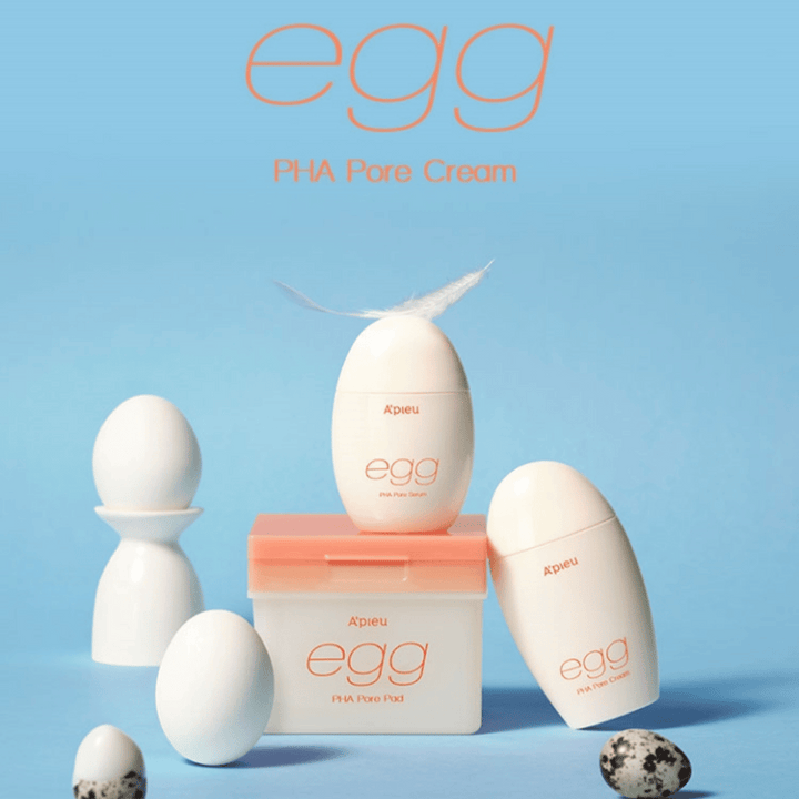 A'pieu Egg PHA Pore-série - des produits en forme d'œuf comme le sérum, la crème et les pads, élégamment arrangés sur un fond bleu avec des œufs et des plumes symbolisant un soin de la peau doux.