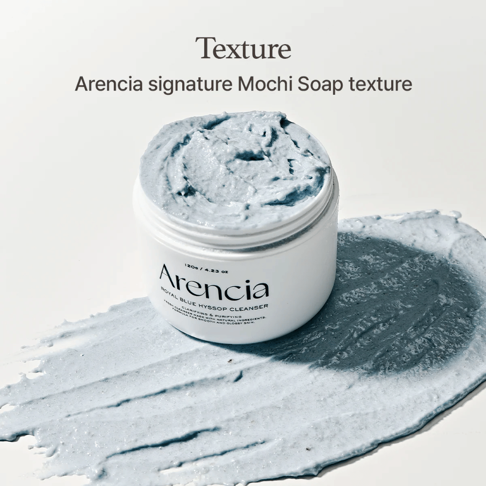 Pot ouvert avec Arencia Fresh Blue Hyssop Rice Mochi Cleanser, placé sur une couche étalée de la formule nettoyante bleue et crémeuse qui montre sa texture semblable à du mochi.
