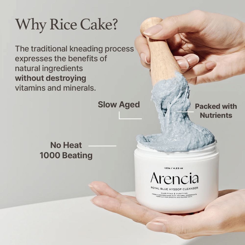 Main tenant le pot nettoyant "Arencia Royal Blue Hyssop Cleanser" avec une cuillère en bois soulevant la pâte nettoyante bleue, semblable à du mochi. Le texte dans l'image décrit les avantages du processus de pâte de riz, tels que "Pas de chaleur", "1000 coups", "Vieilli lentement" et "Riche en nutriments".