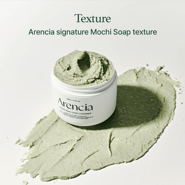 Arencia Fresh Rice Cake Cleanser dans un pot ouvert avec une texture crémeuse verte semblable à du mochi étalée autour du pot sur un fond blanc.