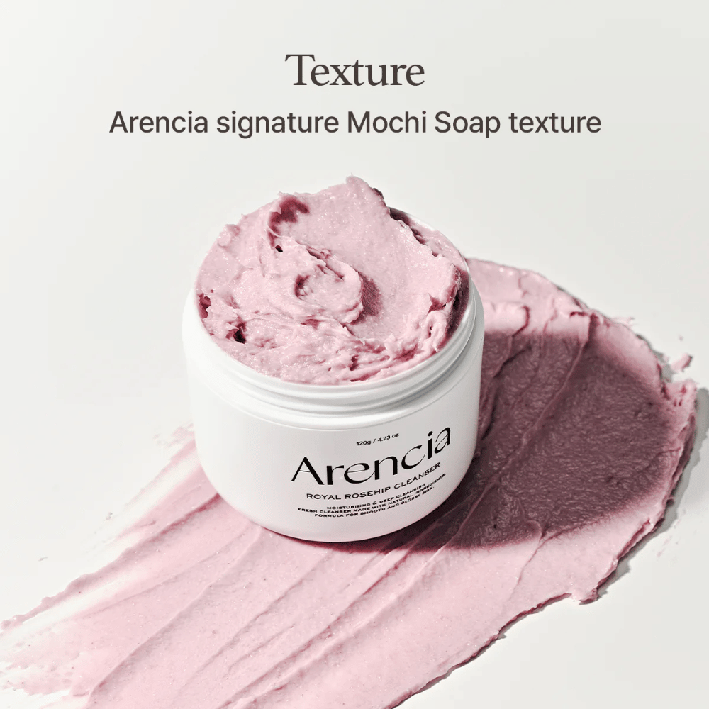 Pot avec Arencia Royal Rosehip Cleanser visible sur un nettoyant rose étalé avec une texture semblable à celle du mochi. Le texte ci-dessus décrit le produit comme la texture signature d'Arencia.