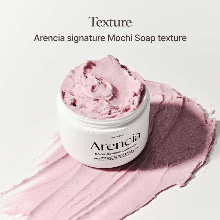 Pot avec Arencia Royal Rosehip Cleanser visible sur un nettoyant rose étalé avec une texture semblable à celle du mochi. Le texte ci-dessus décrit le produit comme la texture signature d'Arencia.