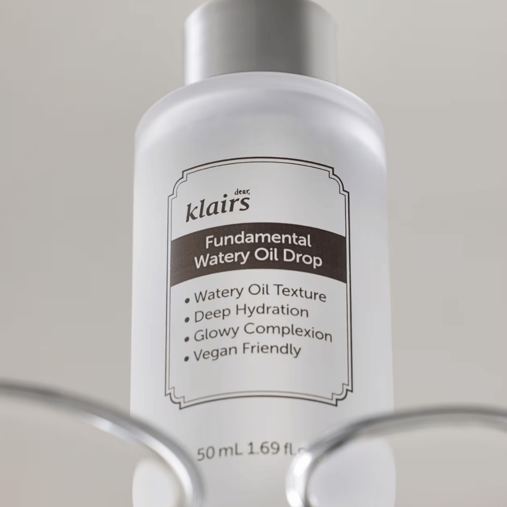 Flacon avec Klairs Fundamental Watery Oil Drop, 50 ml, placé dans un support transparent, avec une étiquette claire mettant en avant les propriétés hydratantes et véganes du produit.